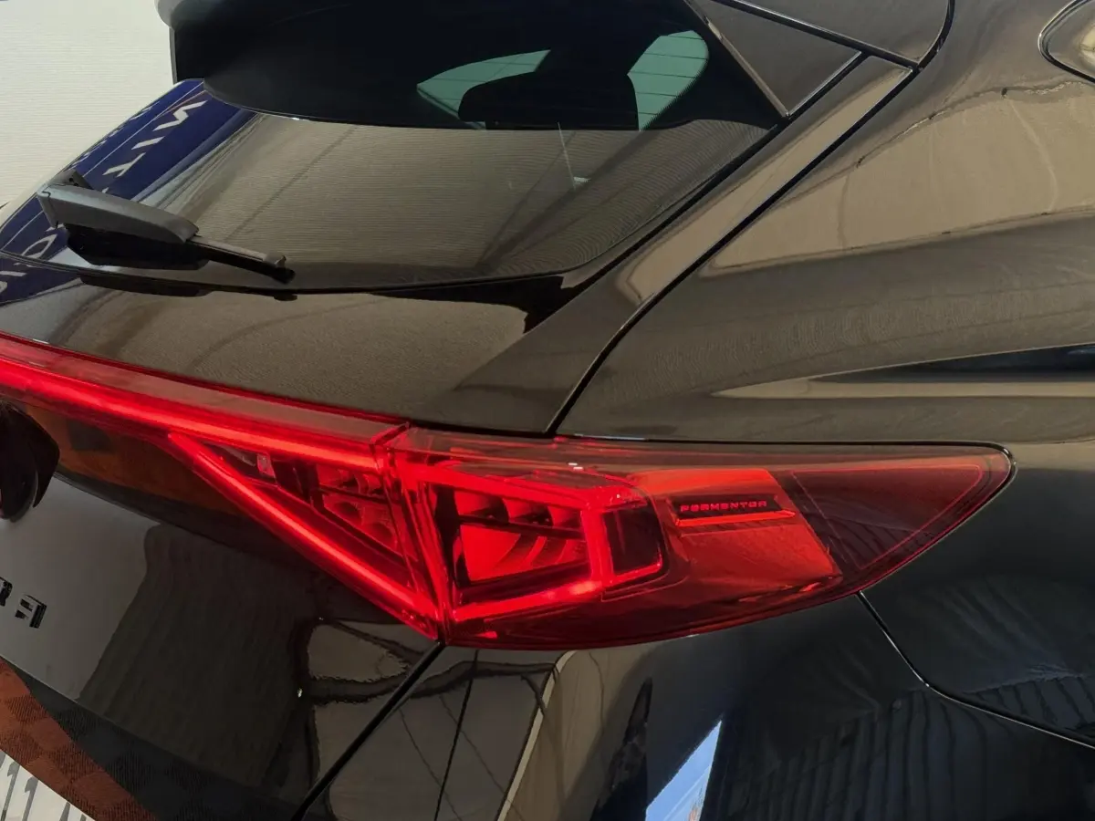 Gros plan sur le feu arrière droit rouge du CUPRA Formentor noir 2023, mettant en valeur le logo et la carrosserie brillante.