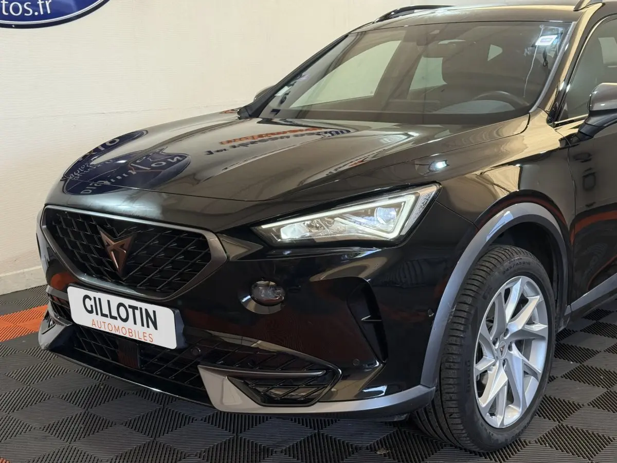 Vue 3/4 avant droit d'un CUPRA Formentor noir brillant avec calandre noire et jantes argentées en exposition intérieure.