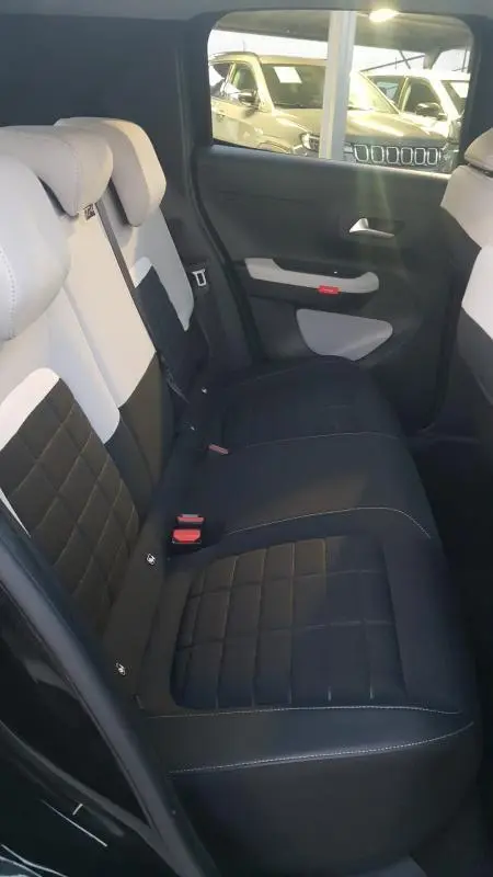 Vue intérieure arrière droite des sièges bicolores noir et blanc de la Citroën C3 Turbo 100 ch 2025 avec habillage de porte assorti.