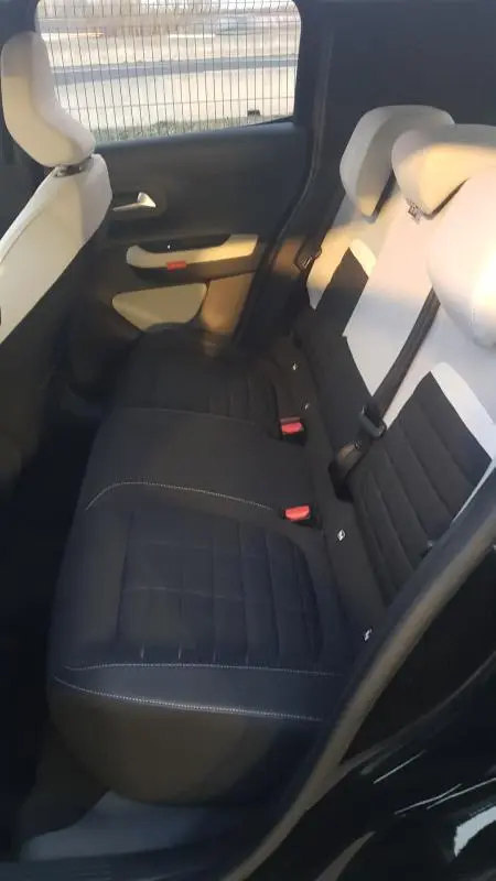Vue intérieure arrière côté gauche de la Citroën C3 noire 2025, montrant les sièges arrière bicolores et les ceintures de sécurité.