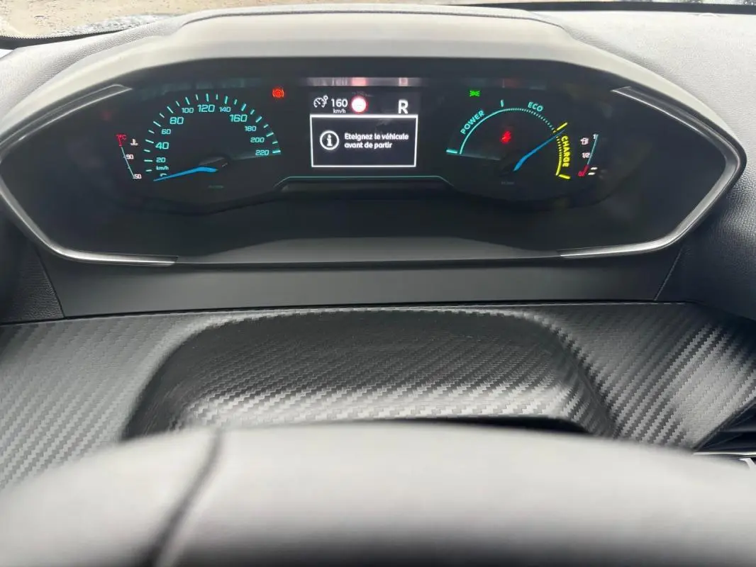 Vue rapprochée du cockpit numérique gris carbone de la Peugeot 208 Hybrid 100 e-DCS6 Style avec affichage digital et jauges colorées.