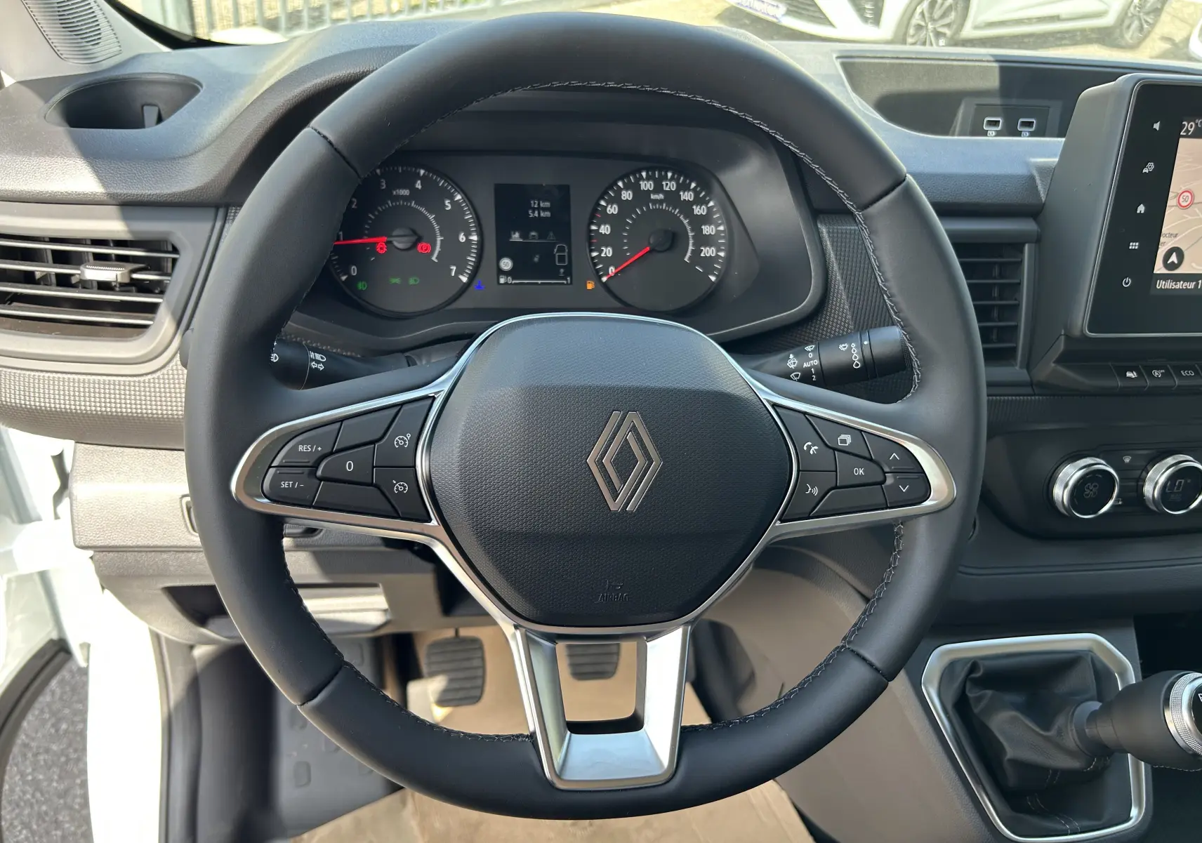 Vue intérieure centrée sur le volant noir du Renault Trafic cabine approfondie 2026 avec tableau de bord et écran tactile.