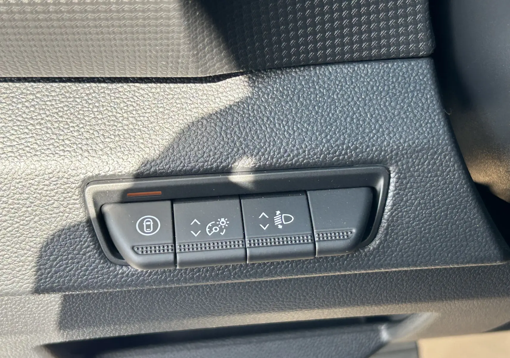 Gros plan sur les commandes de réglage d’éclairage et verrouillage dans l’habitacle noir du Renault Trafic blanc.
