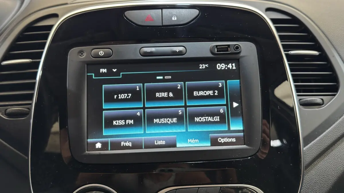 Vue rapprochée de l'écran tactile central noir du tableau de bord du Renault Captur blanc, affichant les stations radio FM.