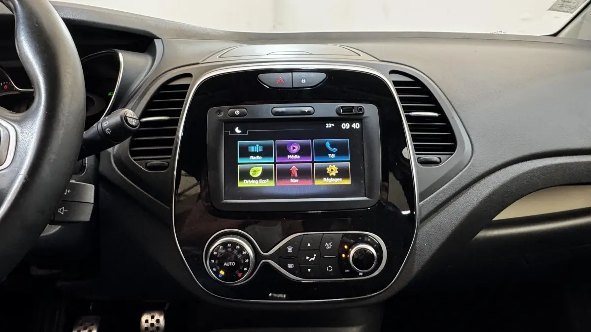 Vue intérieure centrée sur la console tactile noire du Renault Captur blanc 2019 avec commandes climatisation et volant partiel.