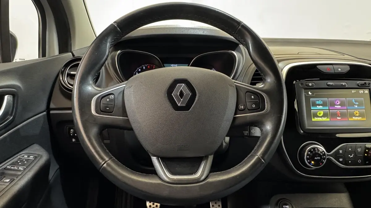 Vue intérieure centrée sur le volant cuir multifonctions et l'écran tactile du tableau de bord du Renault Captur blanc.