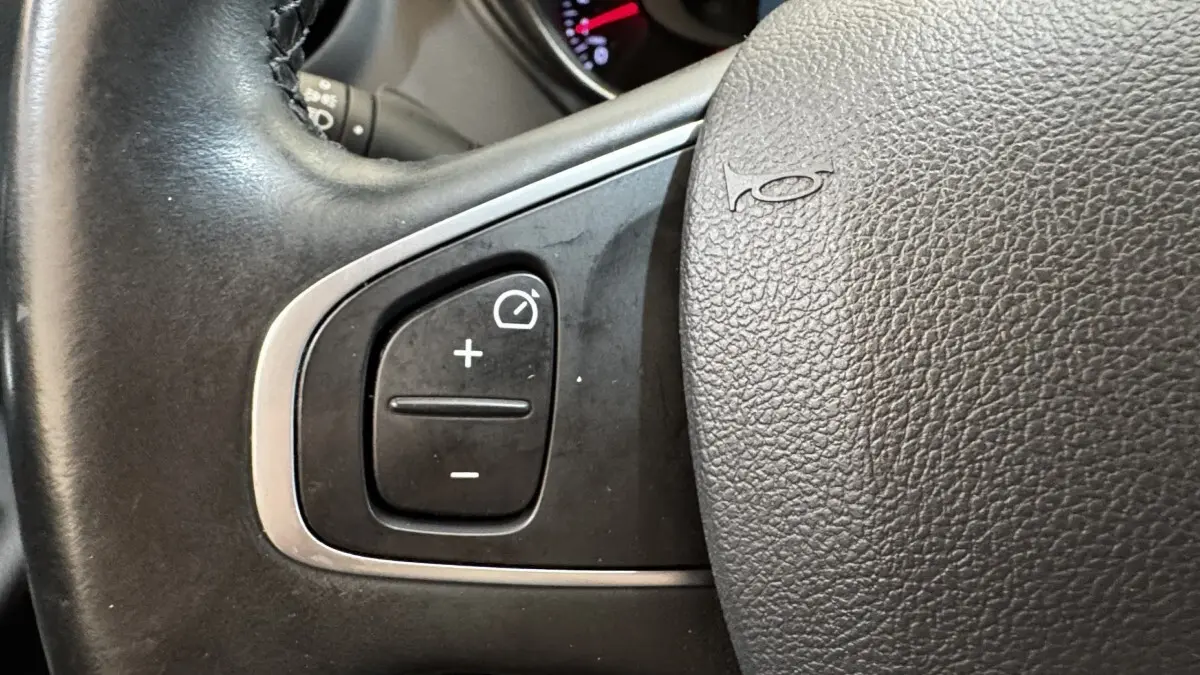 Gros plan sur le volant cuir noir du Renault Captur Intens TCe 90, avec commandes de régulateur de vitesse.