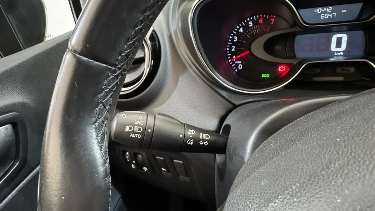 Vue rapprochée du tableau de bord et du volant cuir noir du Renault Captur Intens TCe 90, avec commandes d’éclairage.