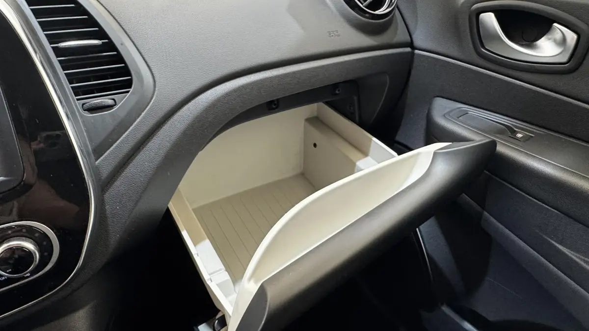 Vue intérieure du coffre à gants ouvert côté passager du Renault Captur Intens TCe 90, tableau de bord noir et garnitures sombres.