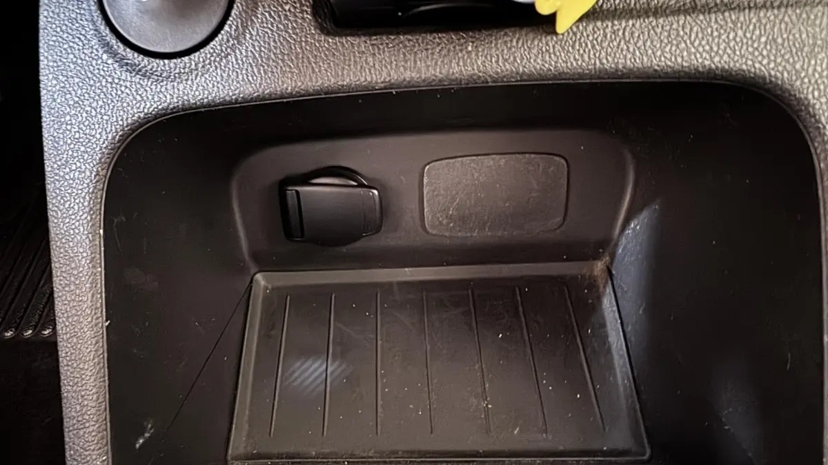 Gros plan sur la prise 12V noire dans le compartiment de rangement intérieur du Renault Captur blanc Intens TCe 90.