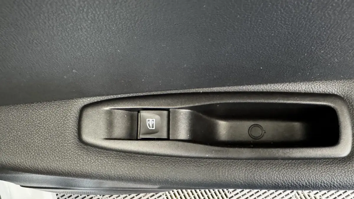 Gros plan sur le bouton de commande de la vitre électrique côté porte intérieure d’un Renault Captur blanc 2019.