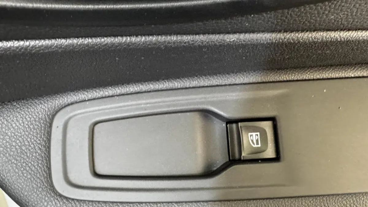 Gros plan sur le bouton de commande électrique de la vitre côté conducteur du Renault Captur blanc Intens TCe 90 2019.