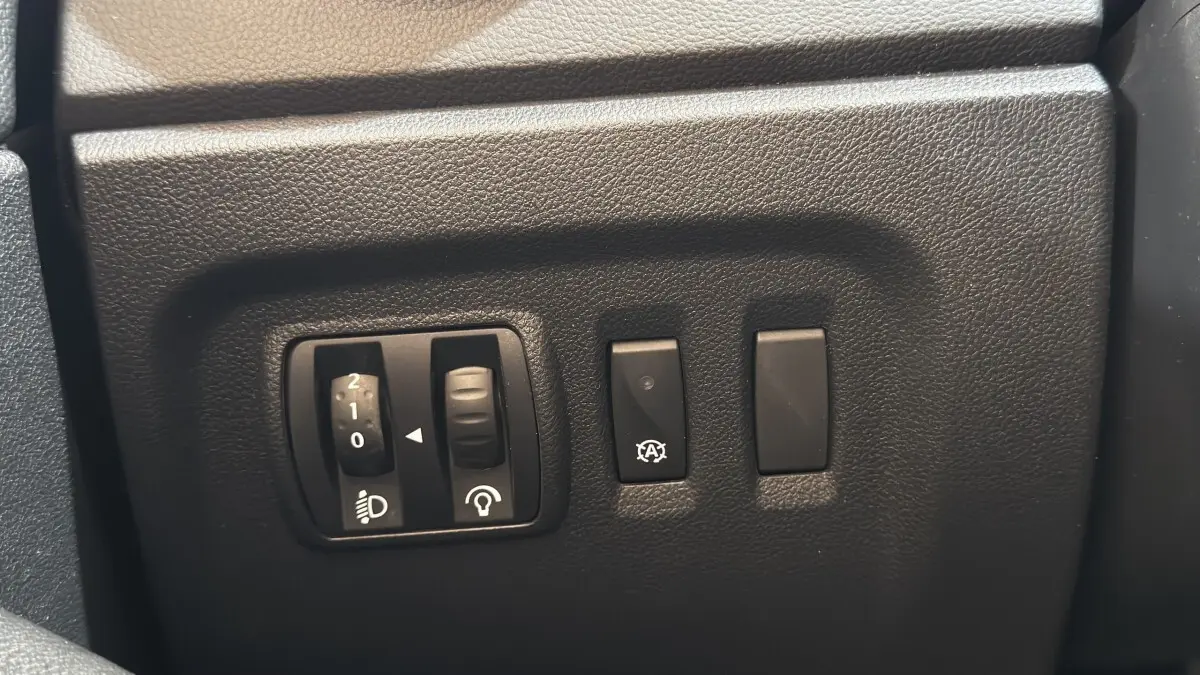 Gros plan sur les commandes de réglage des phares et du tableau de bord du Renault Captur Intens TCe 90 2019.