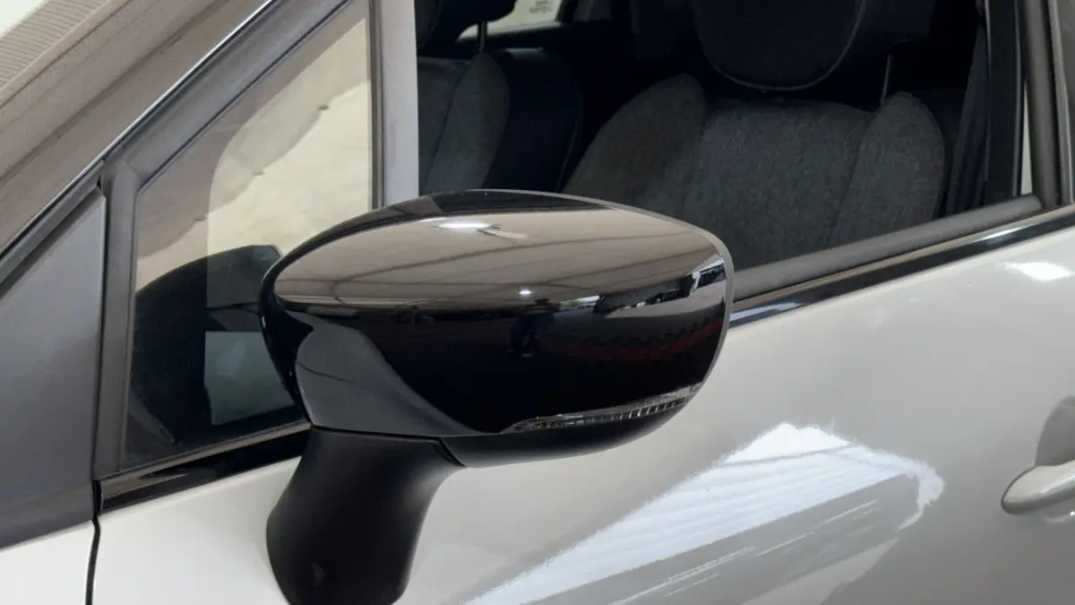Rétroviseur noir en gros plan côté gauche d’un Renault Captur blanc, avec reflet et partie de la portière visible.