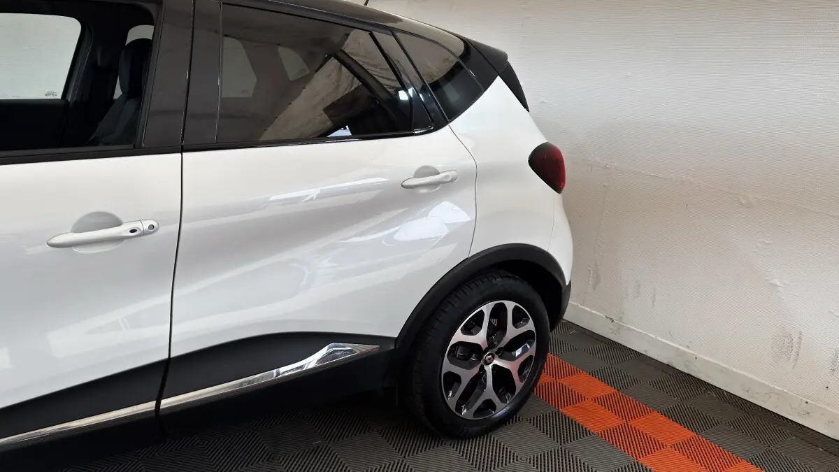 Vue côté arrière droit du Renault Captur blanc 2019 avec toit noir et jantes alliage distinctives.