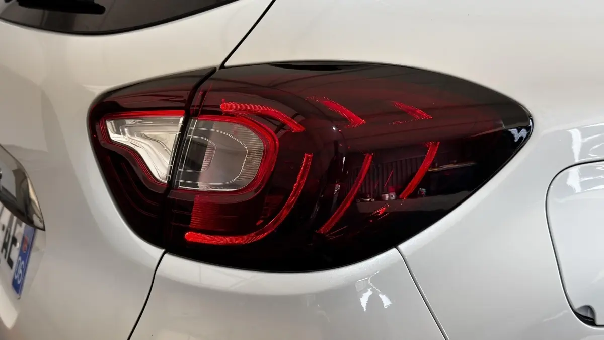 Gros plan sur le feu arrière droit rouge fumé du Renault Captur blanc, version Intens TCe 90 de 2019.