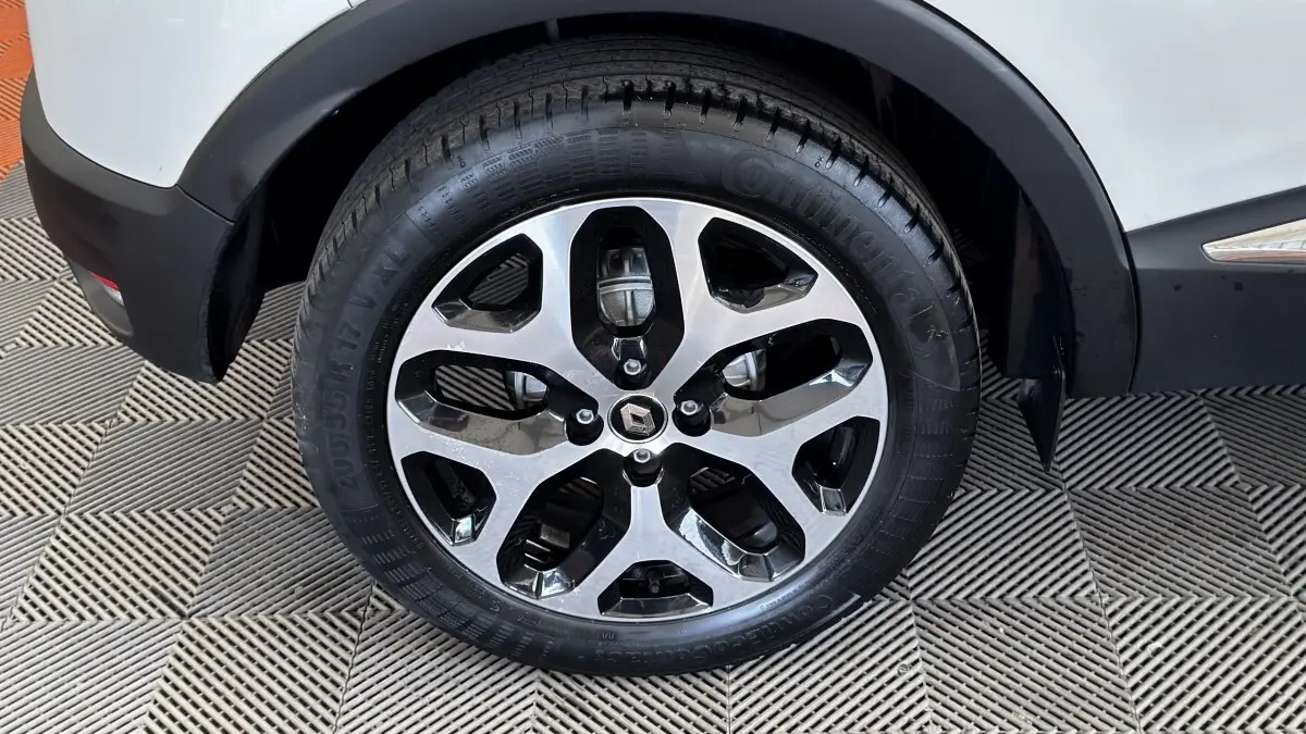 Gros plan sur la roue avant droite du Renault Captur blanc, mettant en valeur la jante alliage bicolore au design moderne.