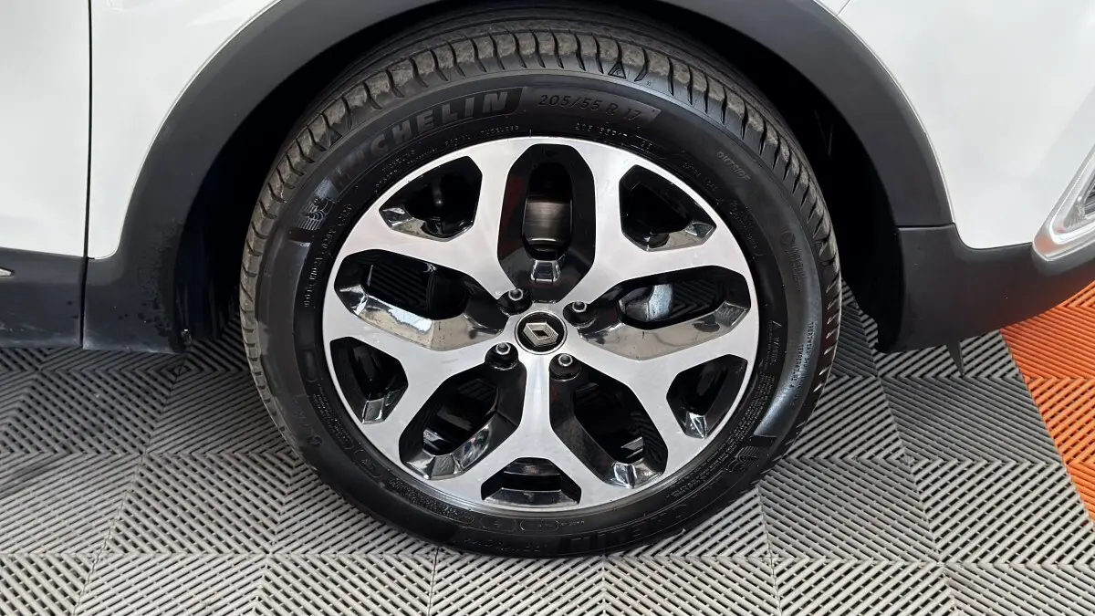 Gros plan sur la roue avant droite du Renault Captur blanc, avec jante alliage bicolore et logo Renault central.