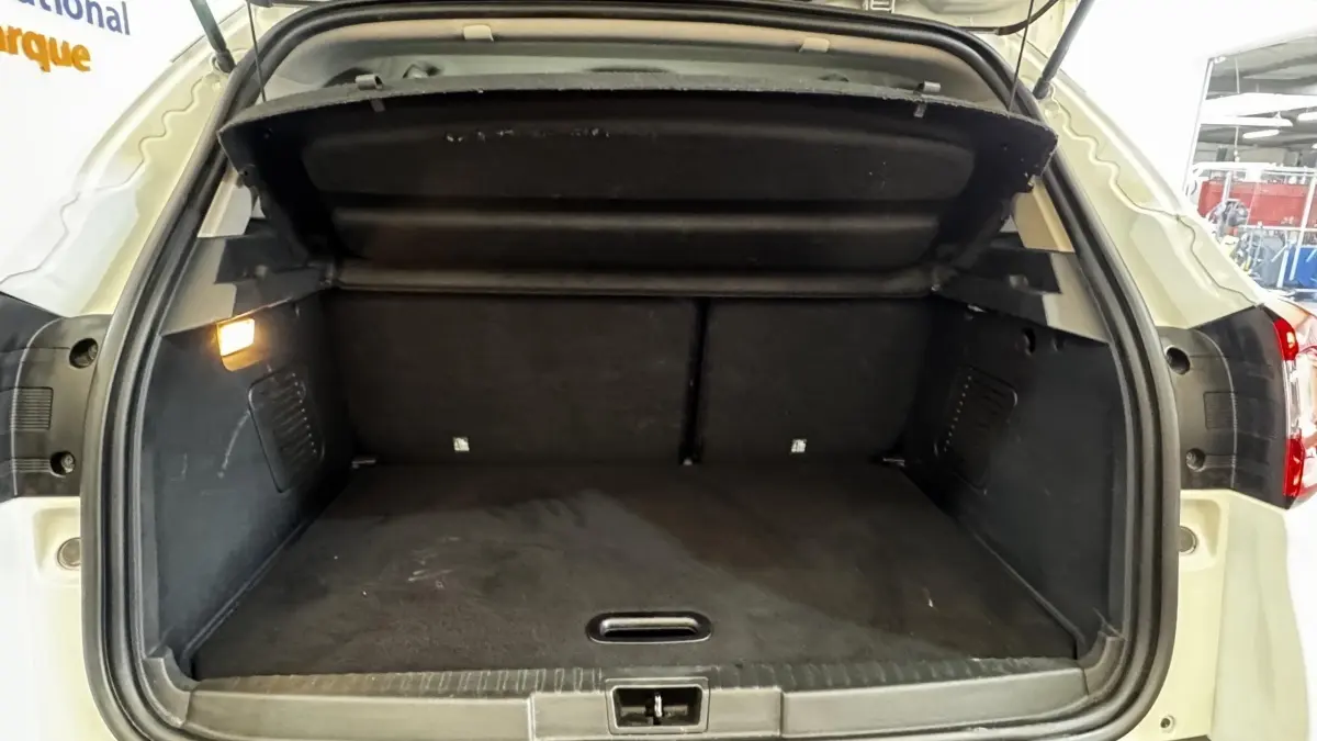 Coffre ouvert vu de l'arrière d'un Renault Captur blanc 2019, avec intérieur de coffre noir et éclairage latéral.