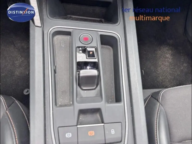 Vue plongeante sur la console centrale noire de la CUPRA Leon 2024 avec levier de vitesse automatique et accoudoirs en tissu noir.