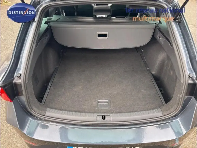 Coffre ouvert vu de l'arrière d'une CUPRA Leon 2024 gris magnétique mat avec cache-bagages rétractable.