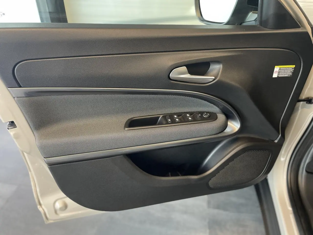 Gros plan sur la porte avant gauche beige métallisé de la FIAT 600 avec commandes de vitres et poignée argentée.