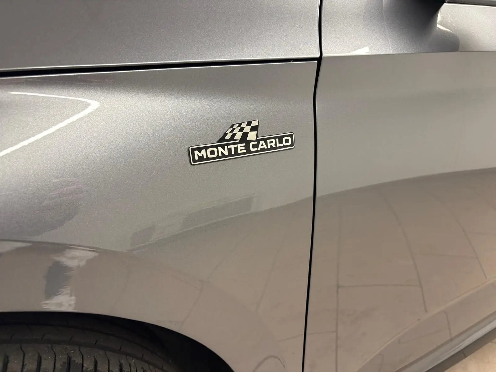 Gros plan sur l'aile avant gauche gris graphite d'un Skoda Kamiq Monte Carlo 2024 avec badge distinctif "Monte Carlo".