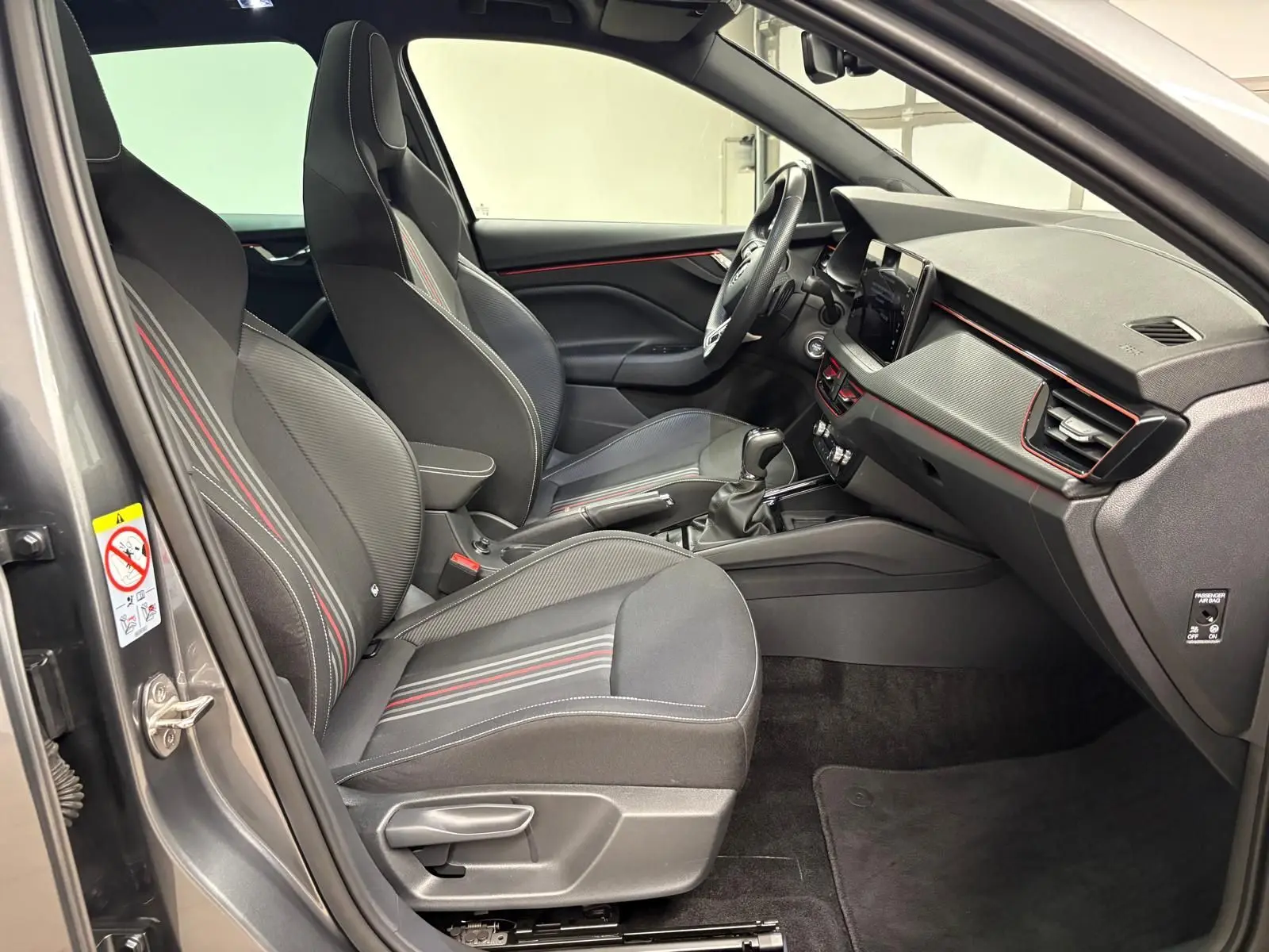 Vue intérieure côté conducteur du Skoda Kamiq 2024 gris graphite, avec sièges sport et détails rouges Monte Carlo.