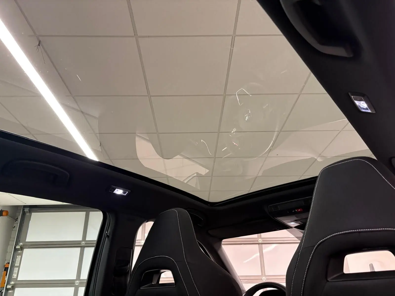 Toit panoramique en verre vu de l'intérieur du Skoda Kamiq Monte Carlo 2024 avec sièges noirs et surpiqûres blanches.