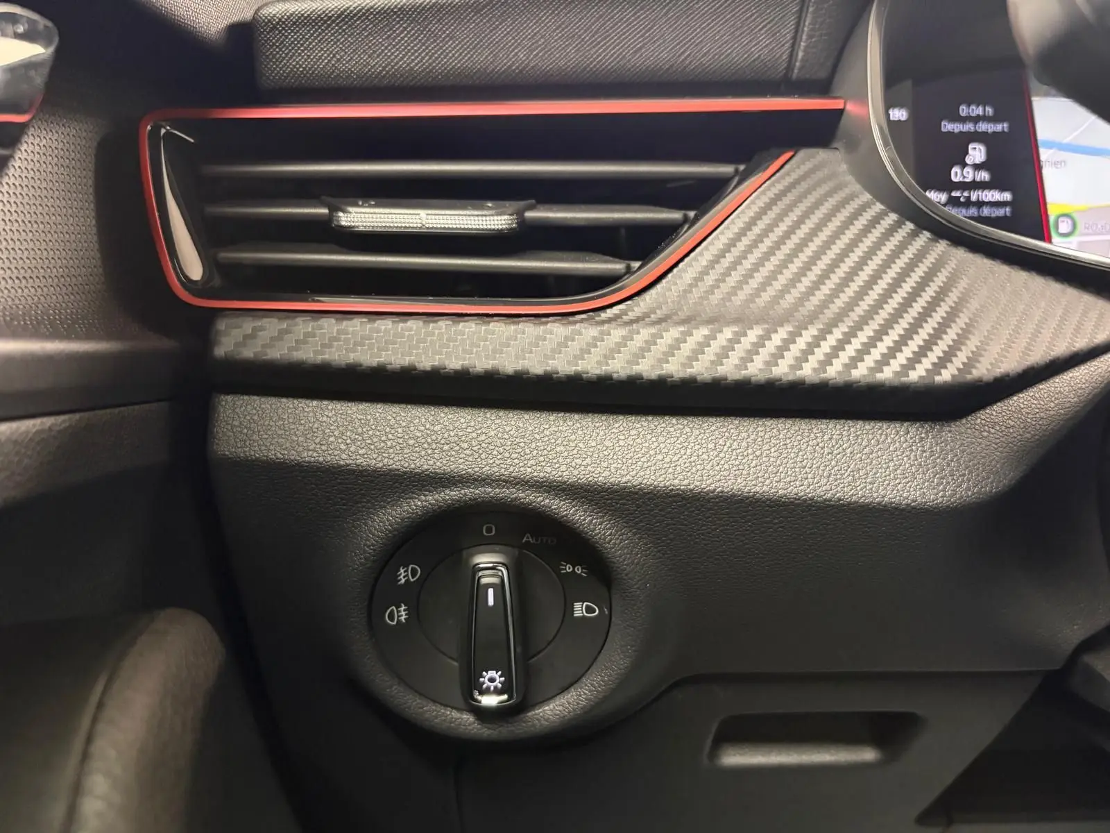 Détail intérieur du tableau de bord du Skoda Kamiq Monte Carlo 2024, avec commande d'éclairage et finition carbone gris graphite.