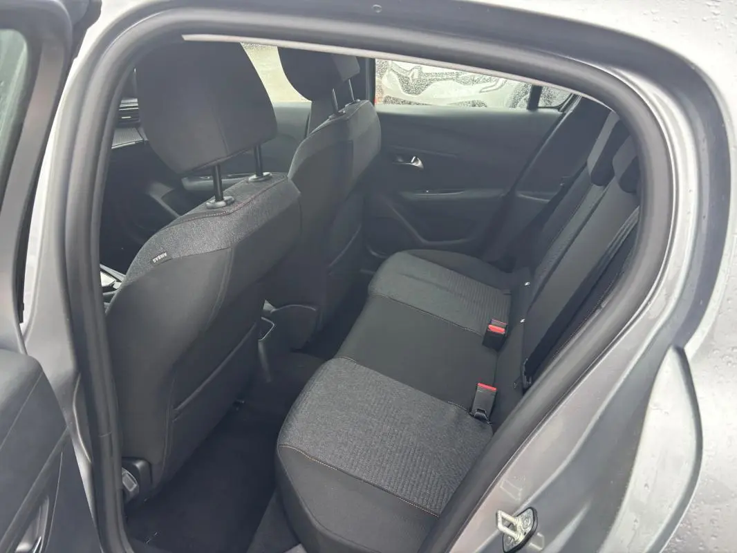 Vue intérieure arrière droite du Peugeot 208 Hybrid gris 2025, montrant les sièges arrière et les portières.