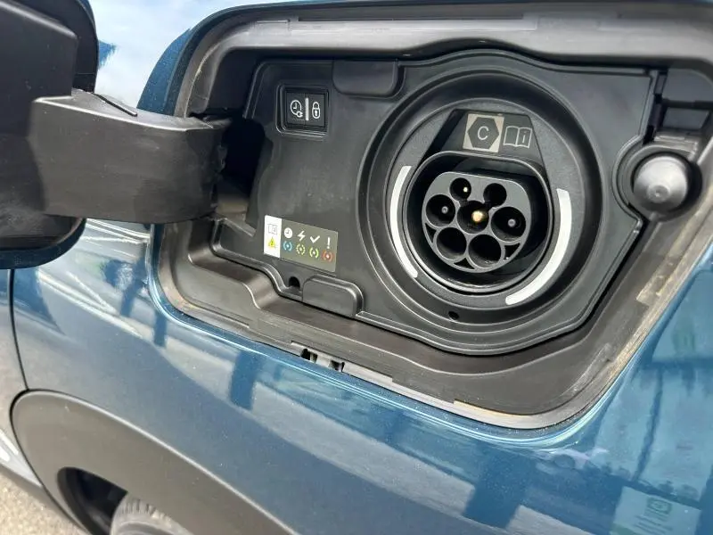 Prise de recharge hybride ouverte côté gauche sur Peugeot 3008 bleu, montrant le connecteur et les commandes intégrées.