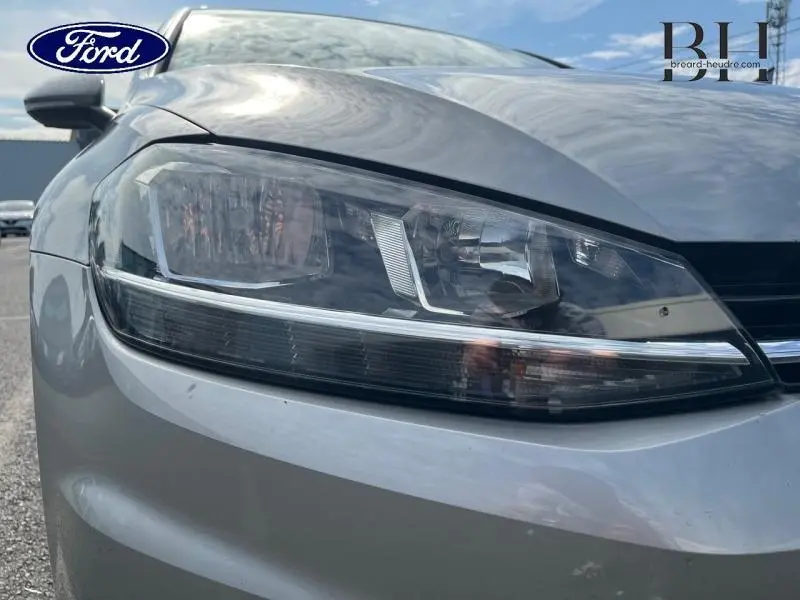 Gros plan sur le phare avant droit d'une Volkswagen Golf SW gris Tungsten, mettant en valeur ses lignes modernes et épurées.