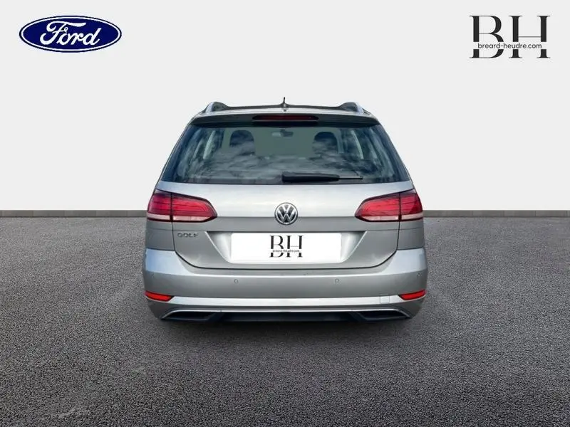 Vue arrière d'une Volkswagen Golf SW gris Tungsten, avec feux arrière LED et hayon fermé sur fond neutre.