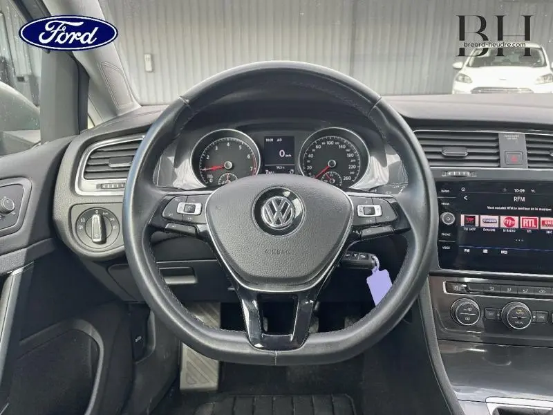 Vue intérieure centrée sur le volant cuir multifonction d'une Volkswagen Golf SW gris Tungsten avec tableau de bord et écran tactile.