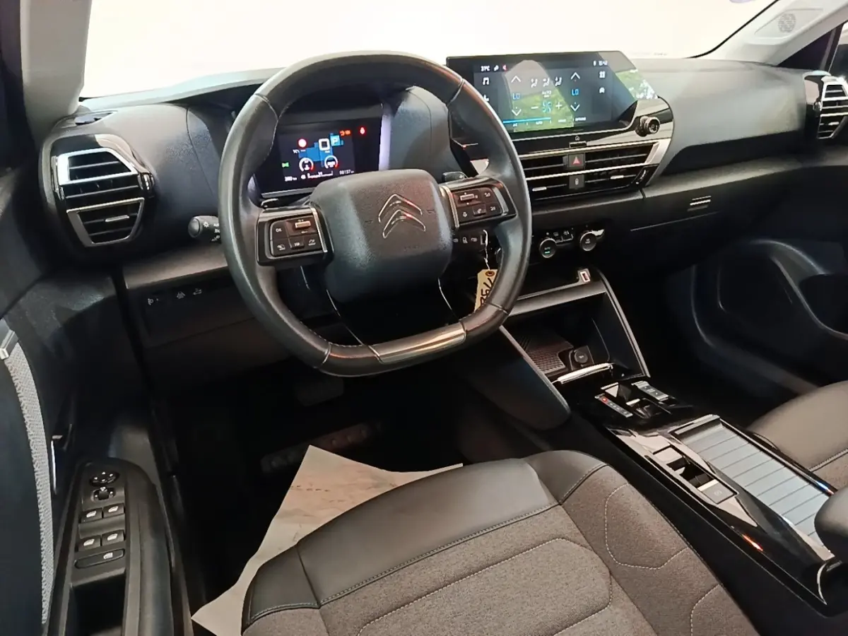 Vue intérieure du poste de conduite de la Citroën C4 X noire, avec volant cuir multifonctions et écran tactile central.