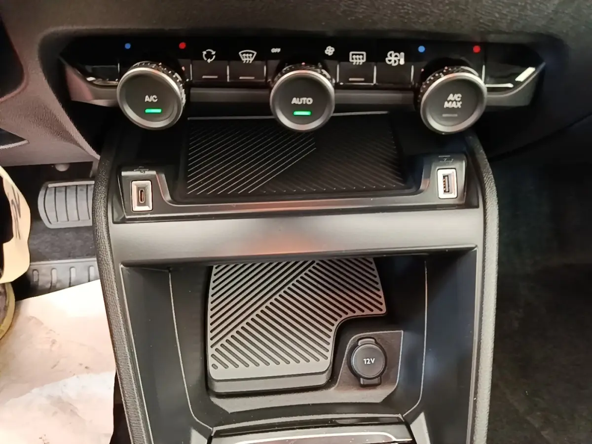 Vue rapprochée de la console centrale noire de la Citroën C4 X 2023 avec commandes climatisation et prises USB et 12V.