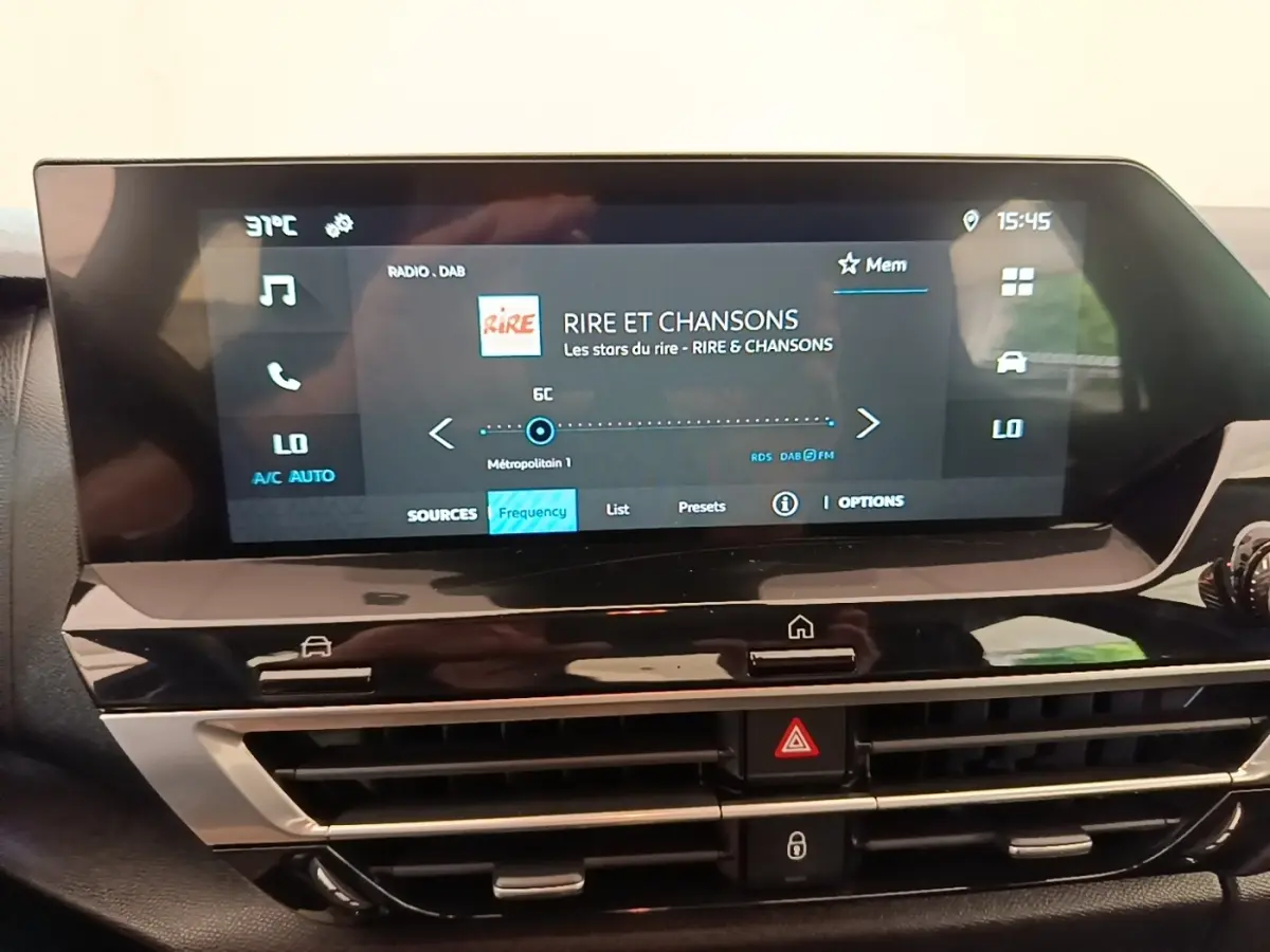 Écran tactile central de la Citroën C4 X noir, affichant la radio et commandes climatisation, vue intérieure frontale.