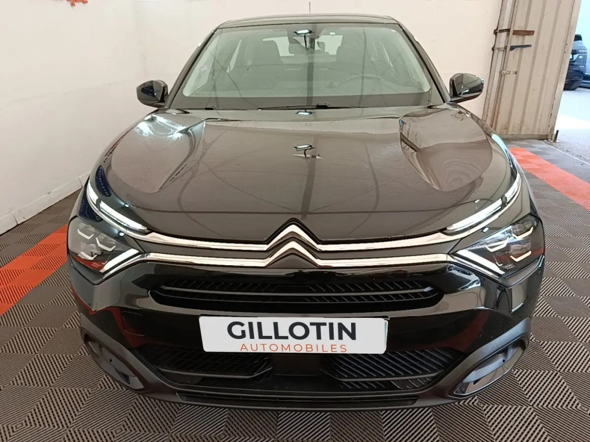 Vue avant d'une Citroën C4 X noire, mettant en valeur sa calandre chromée et ses phares LED distinctifs.