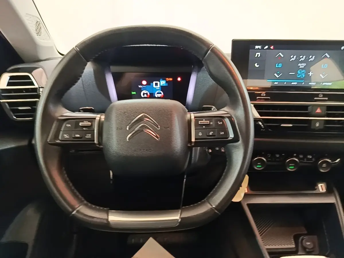 Vue intérieure centrée sur le volant cuir multifonctions noir et l'écran tactile du tableau de bord de la Citroën C4 X 2023.