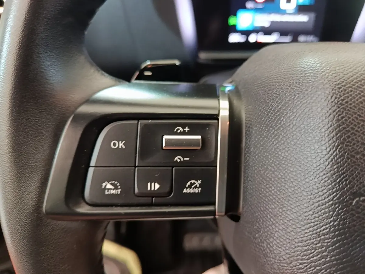 Gros plan sur les commandes multifonctions du volant cuir de la Citroën C4 X PureTech 130 noir, 2023.
