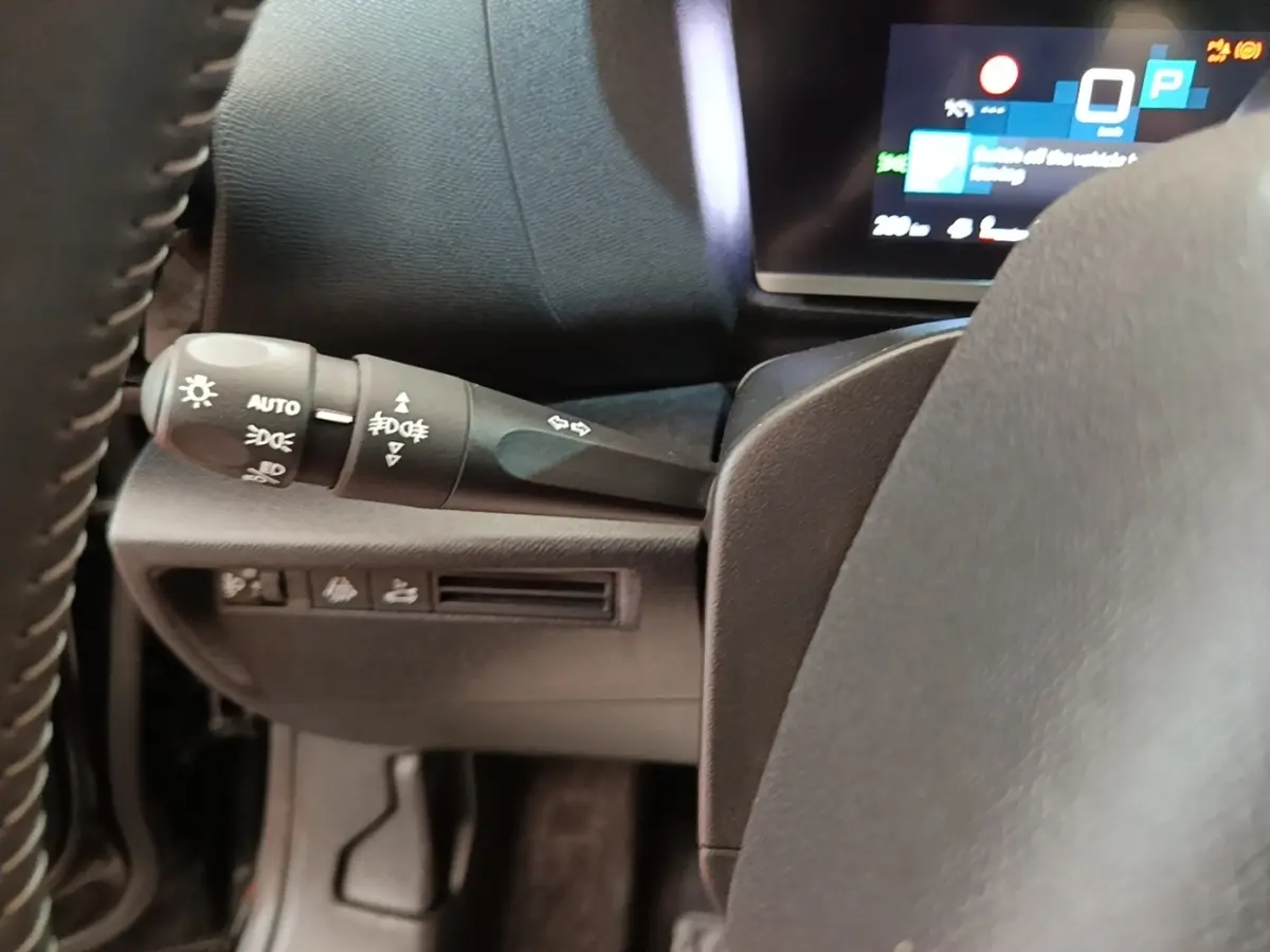 Gros plan sur la commande des phares et clignotants à gauche du volant cuir du Citroën C4 X noir, tableau de bord numérique visible.