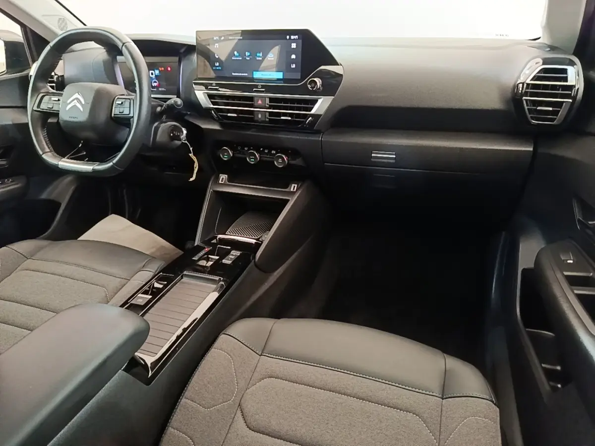 Intérieur noir de la Citroën C4 X 2023, vue de face côté conducteur avec tableau de bord et écran tactile central.