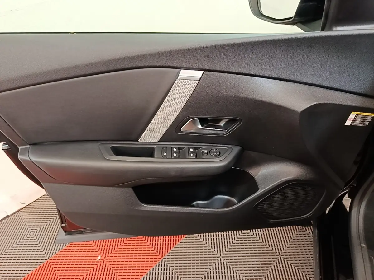 Vue intérieure de la porte avant gauche noire de la Citroën C4 X avec commandes de vitres et haut-parleur intégré.