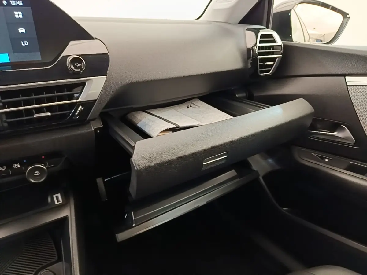 Intérieur de la Citroën C4 X noir, vue côté passager avec boîte à gants ouverte et tableau de bord moderne.