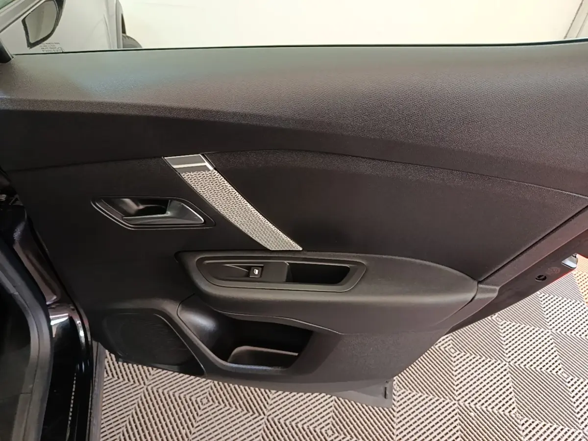 Porte intérieure côté gauche noire de Citroën C4 X 2023 avec poignée et bouton de lève-vitre visible.