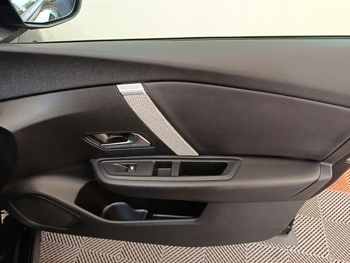 Vue intérieure côté gauche de la porte noire du Citroën C4 X 2023 avec poignée argentée et commande de vitre.