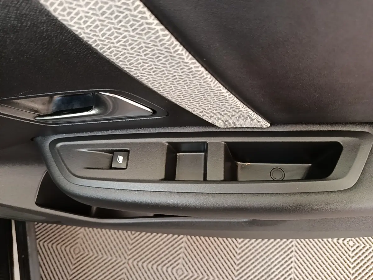 Gros plan sur la poignée intérieure et les commandes de la porte côté gauche d’une Citroën C4 X noire.