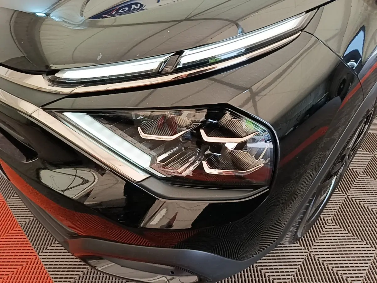 Gros plan sur le phare avant droit noir brillant de la Citroën C4 X 2023 avec détails LED et chrome autour.