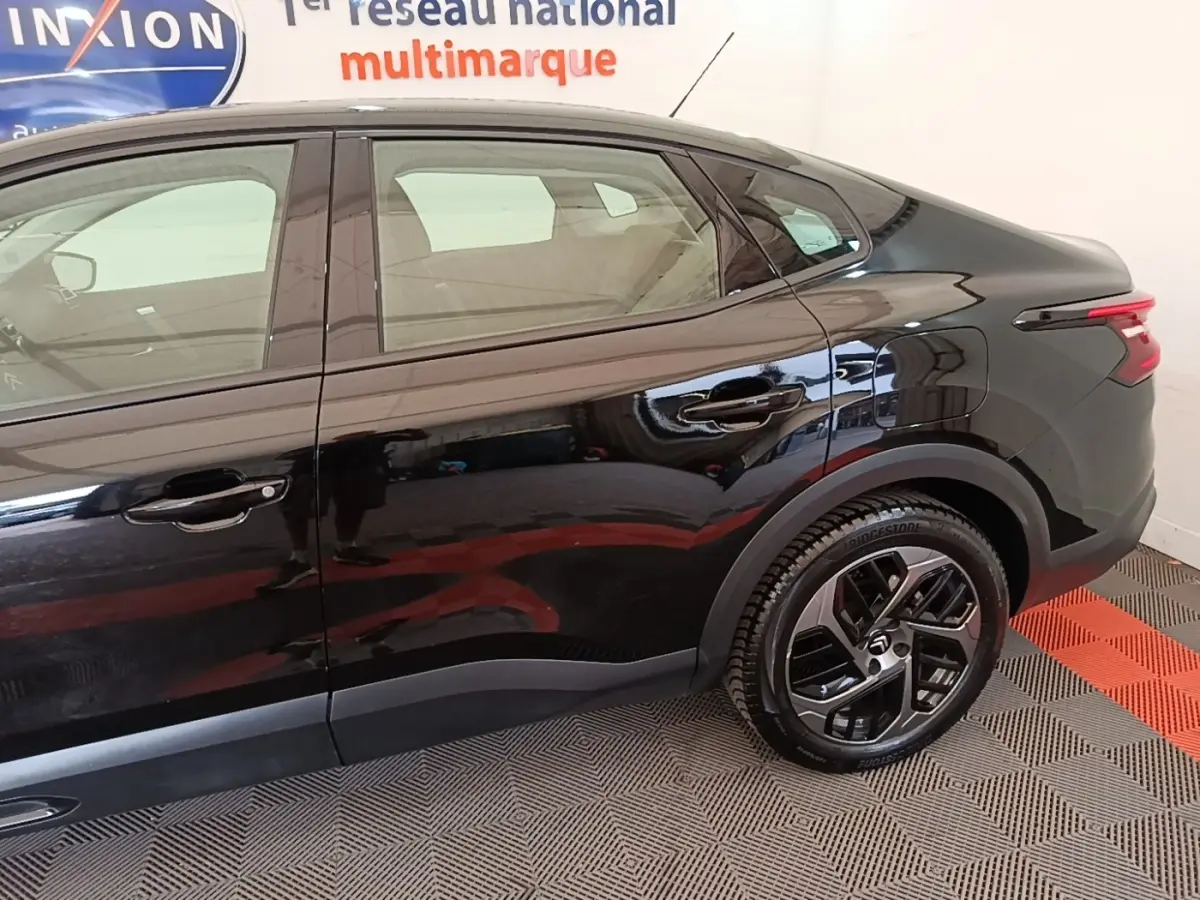 Vue latérale droite de la Citroën C4 X noire 2023, mettant en valeur les jantes et la ligne fluide du toit.